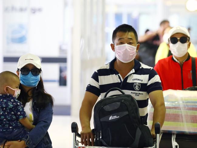 Passengers arriving and departing at Sydney International Airport take precautions by donning a variety of face masks. Picture: Matrix