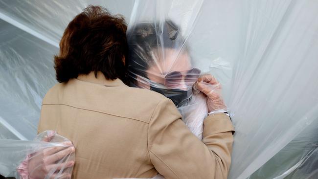 Olivia Grant, right, hugs her grandmother, Mary Grace Sileo through a plastic drop cloth in Wantagh, New York. Picture: AAP