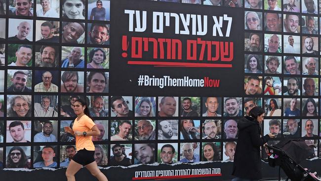 People walk past a billboard bearing the portraits of Israeli hostages held in the Gaza Strip. Picture: AFP.