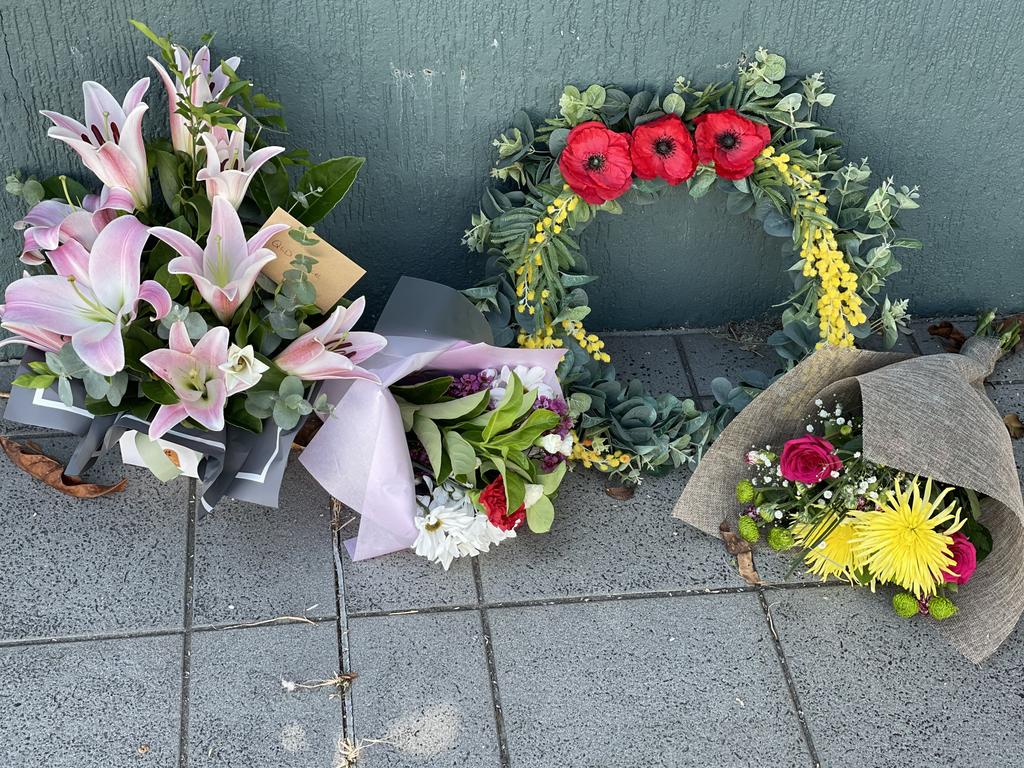 Flowers are laid beneath the two flags flying at half mast outside Mackay Police Station after Constable Rachel McCrow and Constable Matthew Arnold were gunned down along with a neighbour Alan Dare who was also shot and killed at Wieambilla, south of Chinchilla. Photo: Janessa Ekert