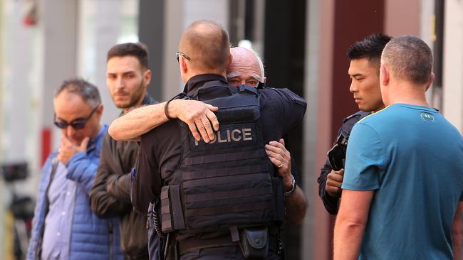 A police officer hugs Mr Pangrazio. Picture Yuri Kouzmin