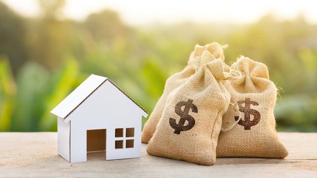 Loan and House concept. Money bags put near house on woodle desk at sunset and green nature background