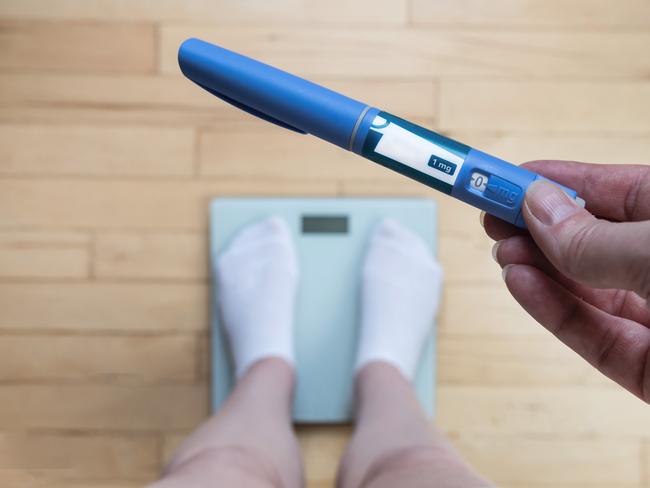 Ozempic Insulin injection pen for diabetics and weight loss. Woman weighs herself and holds Ozempic in her hand. Weight loss concept.