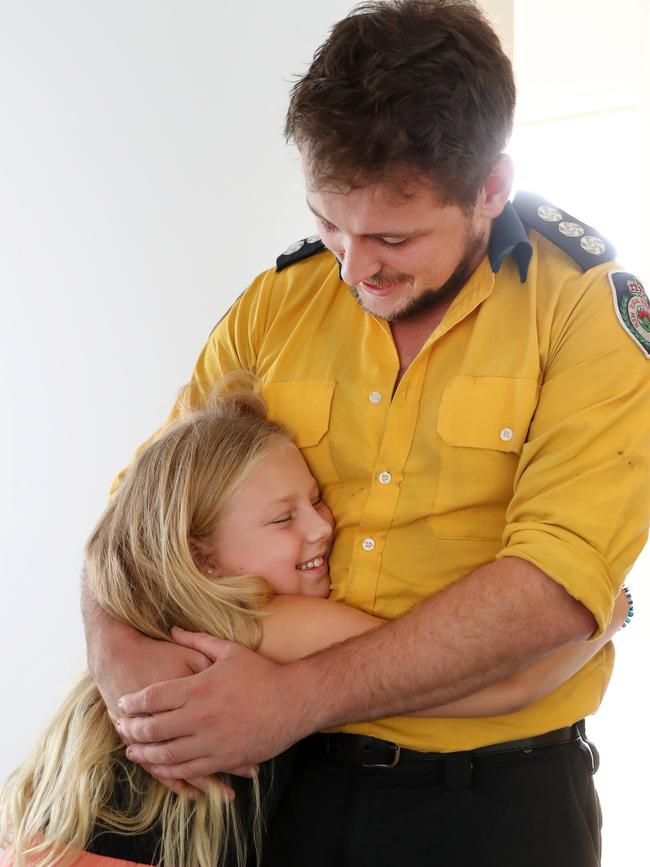 Kesha Pauling, 7, hugs RFS firefighter Nathan Barnden. Picture: Jonathan Ng