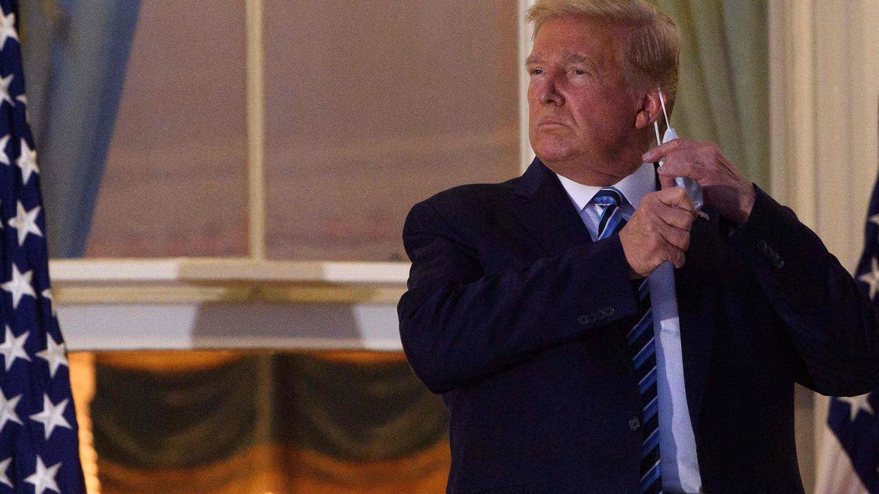 Donald Trump removing his face mask before entering the White House after returning from hospital yesterday. Picture: Nicholas Kamm/AFP