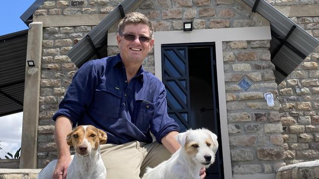 Stuart Barden with his dogs Billy and Maggie outside his hand-built chapel which is now the family home in Kenya. Picture: Supplied