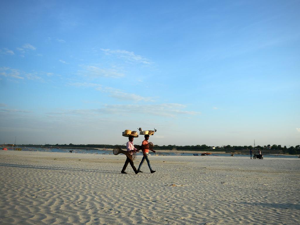 Indian vendors return home after selling snacks at the Sangam the confluence of the Yamuna and Ganga river in Allahabad on July 16, 2018. / AFP PHOTO / SANJAY KANOJIA