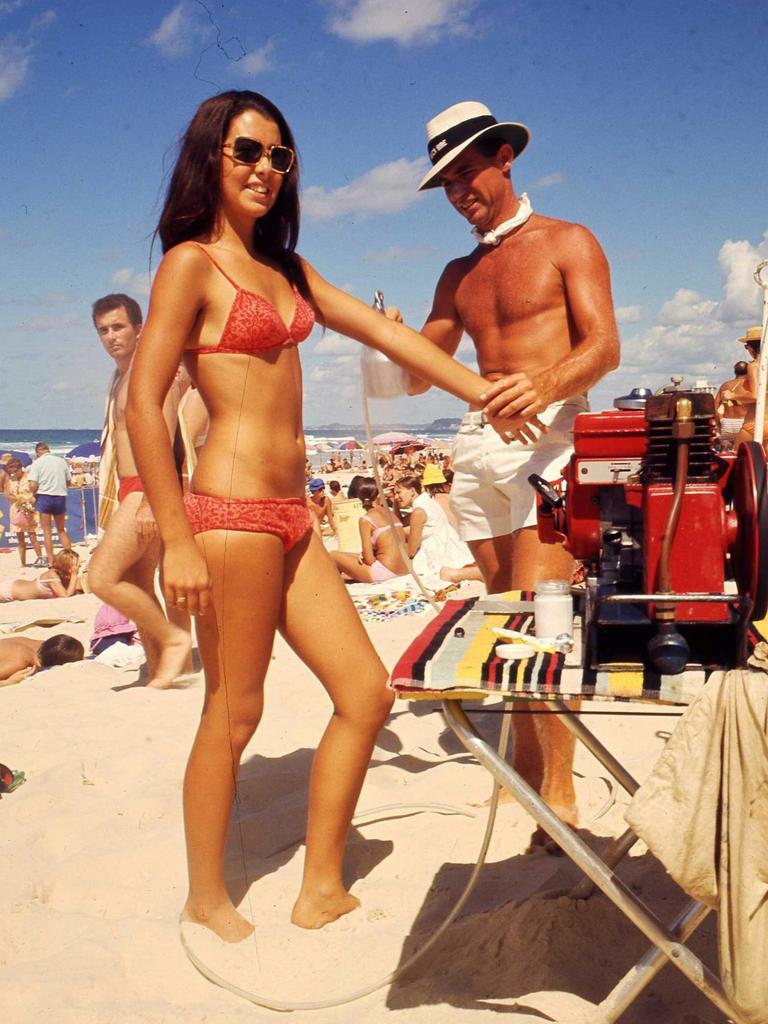 1970 - A bikini-clad beach girl getting a spray tan on Surfers Paradise Beach.