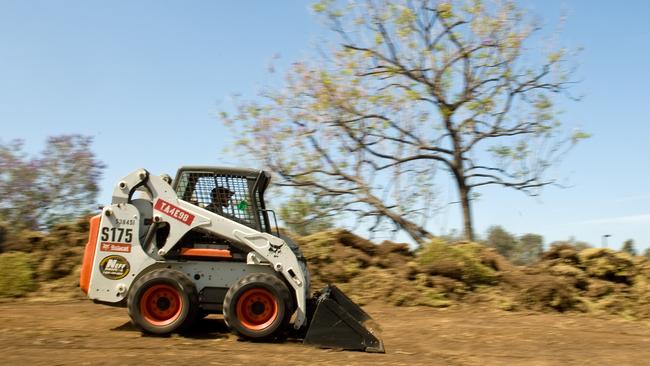In this Monday, June 1, 2015 photo, Brandon Amos with JW Landscape zips around on a Bobcat loader as he pulls up the grass at Suzuki headquarters in Brea, Calif. The company will be installing drought-tolerant plants, saving an estimated 700,000 gallons of water a month, said R.F. Taitano, administrative services manager. California cities and businesses have been ordered to reduce water use by 25 percent, because of the drought. (Mindy Schauer/The Orange County Register via AP)