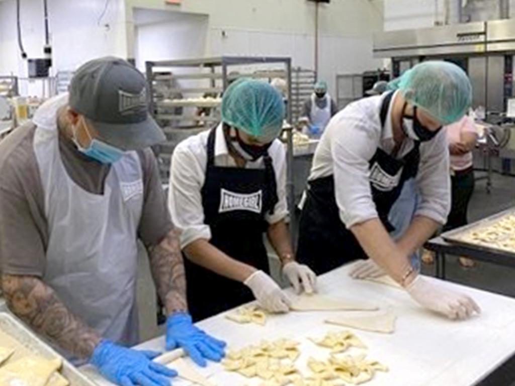 Prince Harry and Meghan, pictured here alongside ex-gang members at a Los Angeles bakery, have busied themselves volunteering. Picture: Instagram