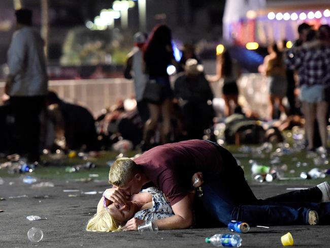 A man lays on top of a woman as others flee the Route 91 Harvest country music festival grounds in Las Vegas. Picture: Getty Images