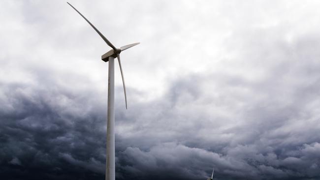 wind turbines against dark clouds in the upcoming storm, concept for renewable energy or increasing complications by the protest of wind power opponents, selected focus