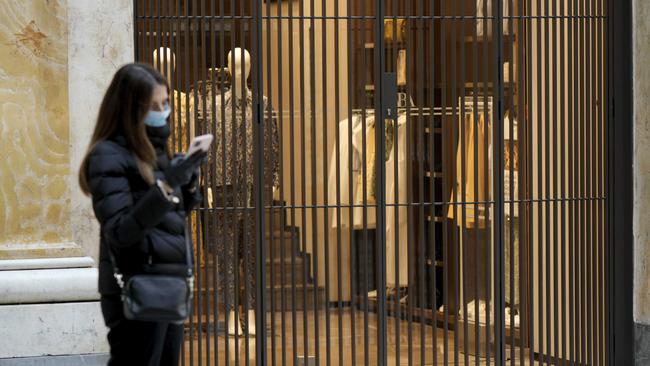 A woman checks her smartphone outside a closed clothes store in Naples. Picture: AP