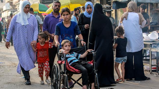 A girl pushes a boy sitting in a wheelchair along a market street in Deir el-Balah in the central Gaza Strip. Picture: AFP