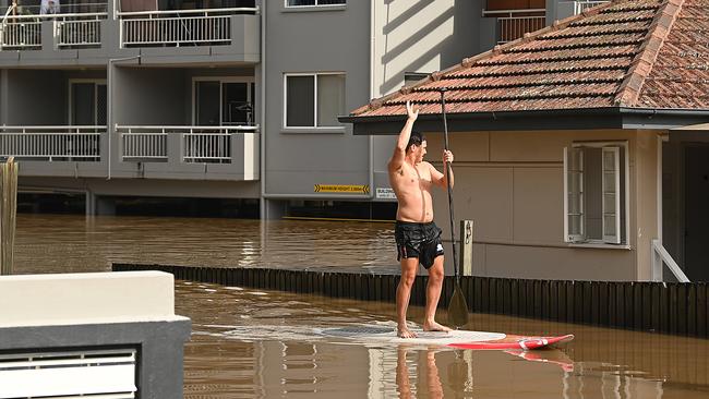 Students paddle around their flooded apartment blocks in St Lucia after floods and rain swamped Brisbane. Picture: Lyndon Mechielsen.