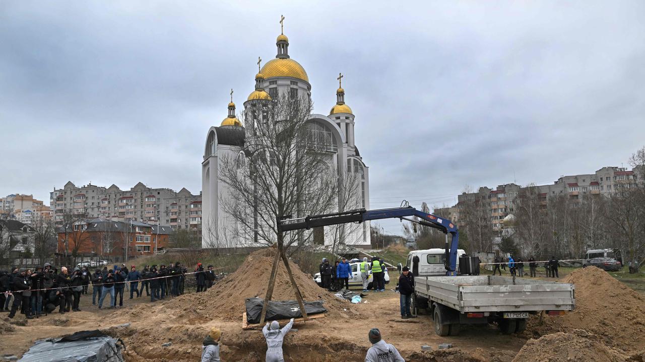 Journalists gather as bodies are exhumed from a mass-grave in the grounds of the St Andrew and Pyervozvannoho All Saints church in the Ukrainian town of Bucha, northwest of Kyiv. Picture: Sergei Supingsky/AFP