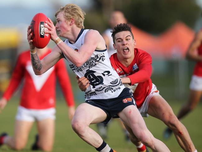 South's Mark Noble gets tackled by North's Connor Rozee at Noarlunga Oval last month.