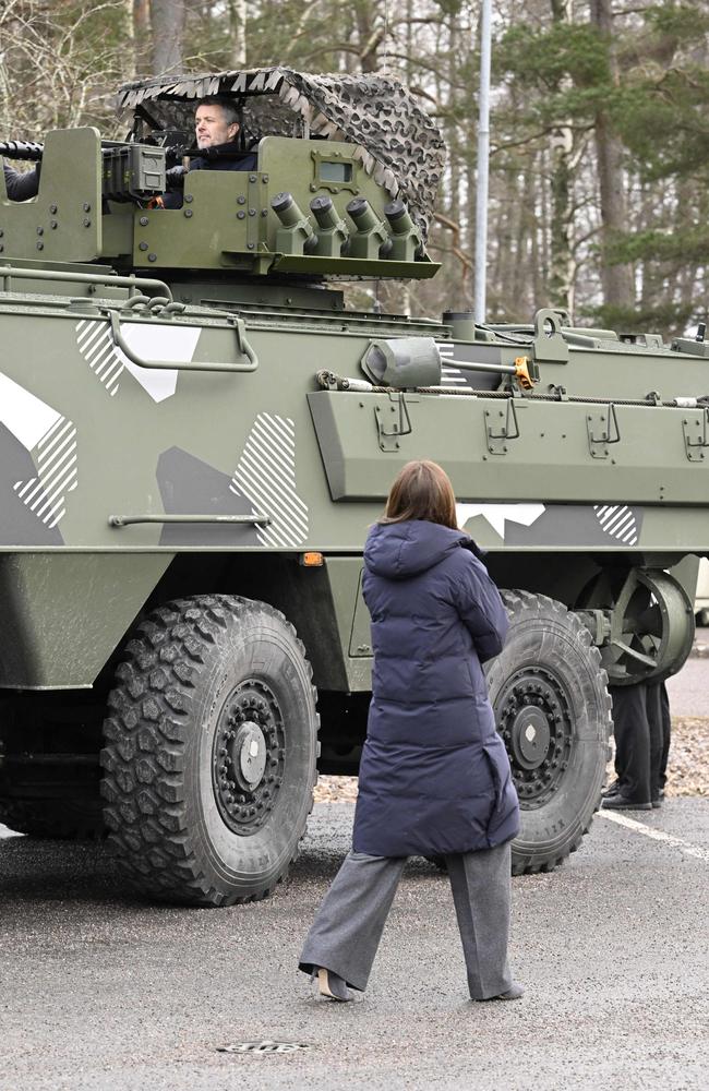 Queen Mary of Denmark looks at King Frederik X of Denmark who peeks out of the turret on the top of the Patria 6x6 armoured vehicle. Picture: AFP / Finland OUT