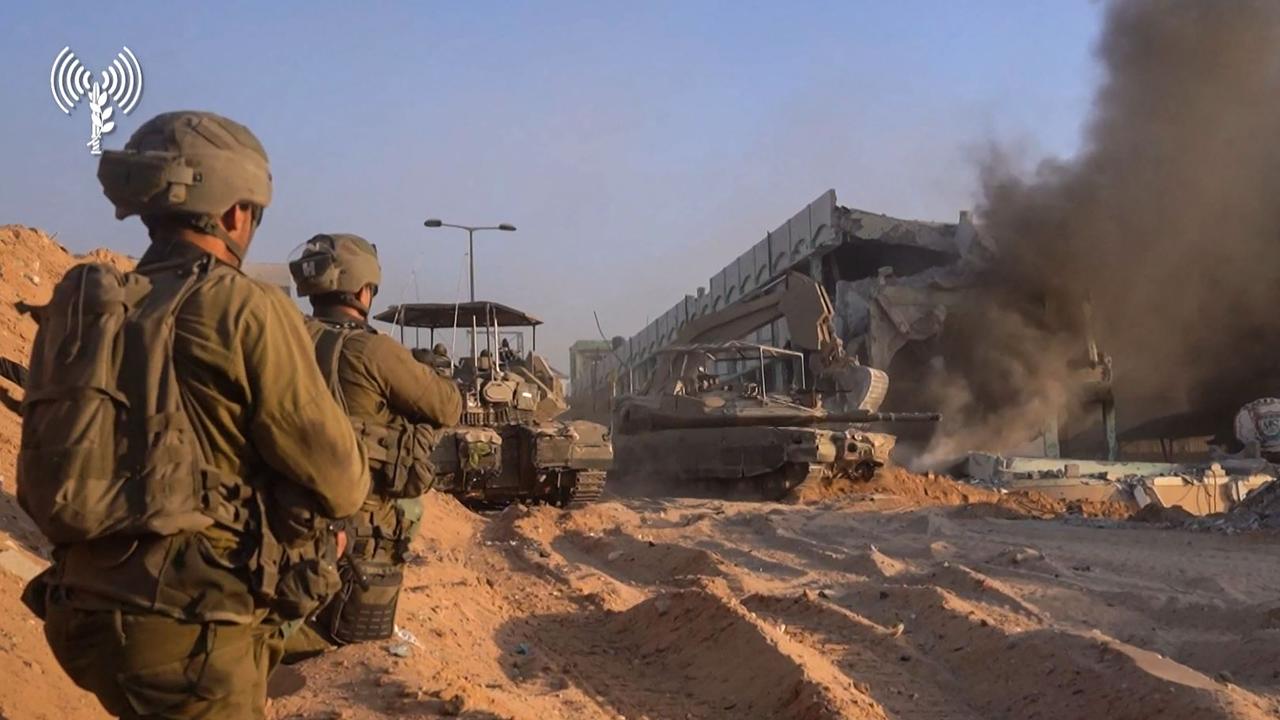 Israeli troops taking position as an army bulldozer demolishes a burning building inside the Gaza Strip. Picture: AFP