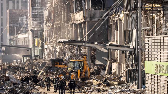 Ukrainian firefighters and servicemen work next to a digger amid the rubble of the Retroville shopping mall. Picture: AFP