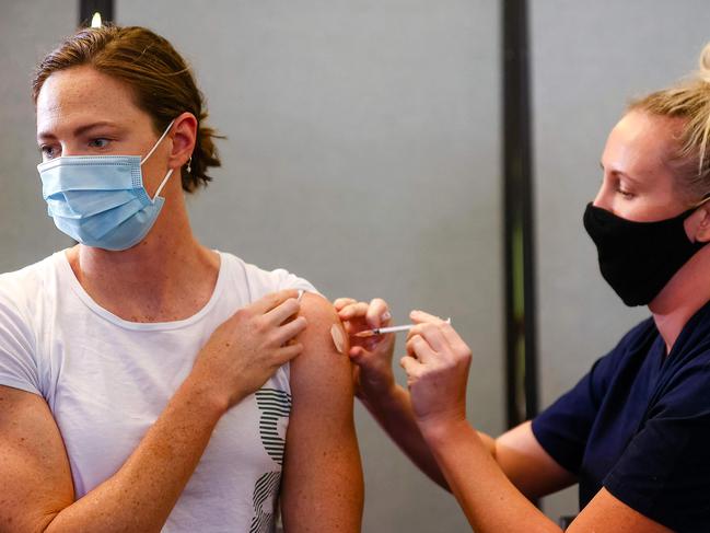 Three time Olympian Australian swimmer Cate Campbell (L) receives her dose of Pfizer/BioNTech vaccine against Covid-19 at the Queensland Sports and Athletics Centre in Brisbane on May 10, 2021, after the Australian Olympic Committee began their rollout of vaccinations for members of the Olympic team ahead of the the games in Tokyo. (Photo by Patrick HAMILTON / AFP) / IMAGE RESTRICTED TO EDITORIAL USE - STRICTLY NO COMMERCIAL USE