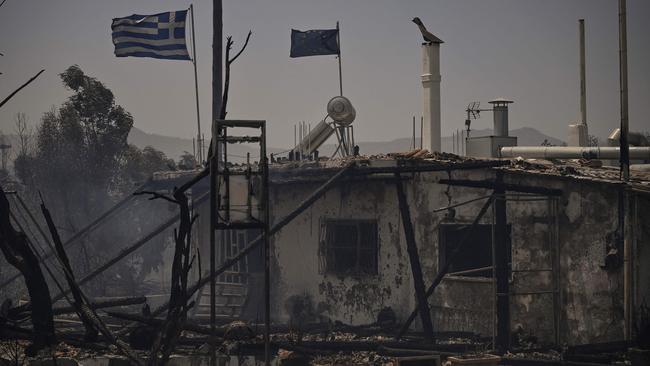 Fluttering Greek and European flags on a burnt building amid a fire between the villages of Kiotari and Genadi, on the Greek island of Rhodes. Picture: AFP