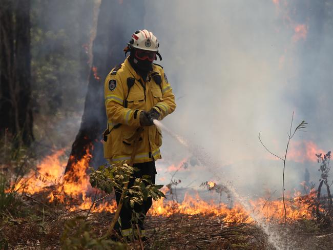 A Rural Fire Service volunteer battles flames on the NSW south coast.