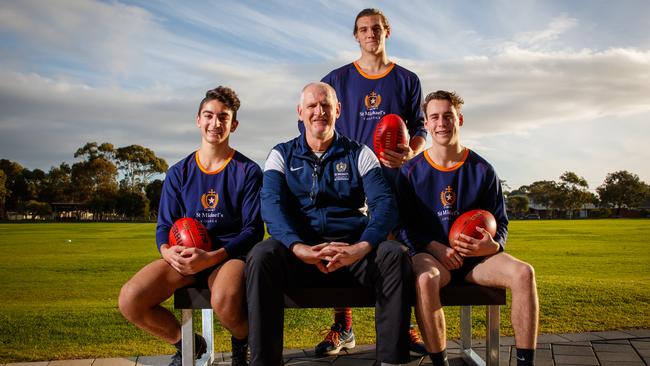 SA Football Hall of Famer Mark Mickan with St Michael’s College players John Moschou, Indiana Dorian and Jack Balkwill. Mickan is back coaching the school after having groundbreaking Parkinson's disease surgery in April. Picture: Matt Turner