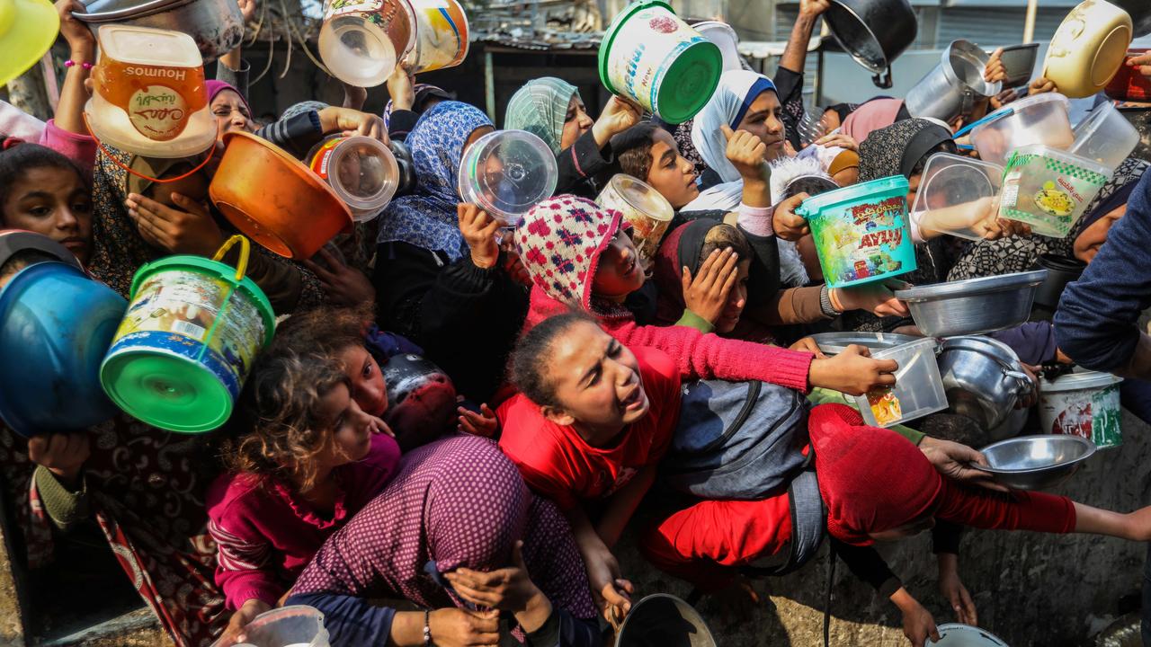 People queue for food handouts distributed during wartime in Rafah, Gaza. Picture: Ahmad Hasaballah/Getty Images.