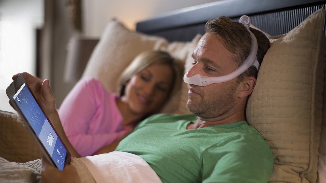 A patient using a sleep apnoea mask and app to stay engaged with their sleep therapy.