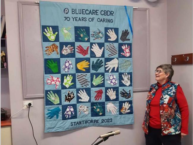 BlueCare Stanthorpe volunteer Jacki Harvey unveiling the hands of BlueCare Stanthorpe wall hanger at the 70th anniversary celebrations.