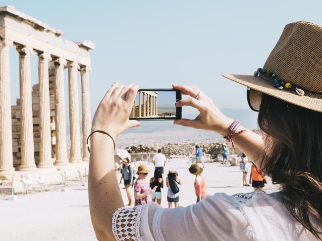 Athens, Greece. Woman taling a picture with a smartphone to The Erechtheion temple in the Acropolis of Athens.Escape 14 May 2023Doc HolidayPhoto - Getty Images