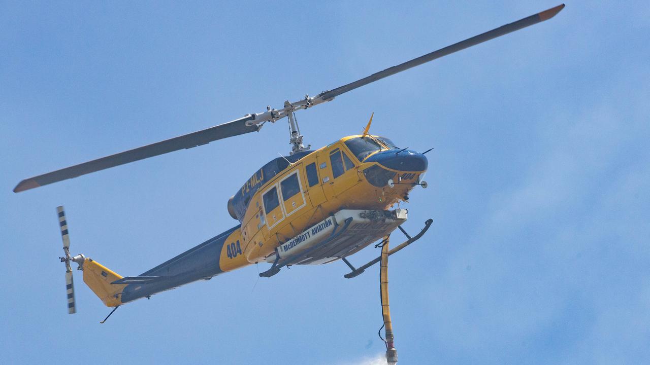 A helicopter works to contain a bushfire at the southern end of Peregian Beach on the border with Coolum Beach, Queensland, Wednesday, October 23, 2019. The fire started north of the Coolum High school and travelled north towards the beach. (AAP Image/Rob Maccoll) NO ARCHIVING