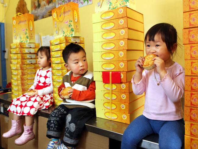 Sophia Tran, 3, Alex Lam, 2, and Fiona Kuch, 2, enjoying an early tasting of moon cakes that have been baked for the Cabramatta Moon Festival at the An Phat Bakery.