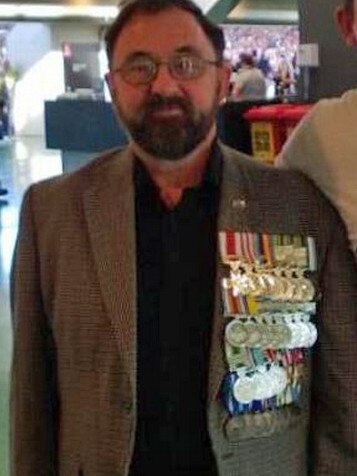 A medal festooned Neville Donohue poses for photos as the ANZAC Day match between Collingwood and Essendon at the MCG in 2013.