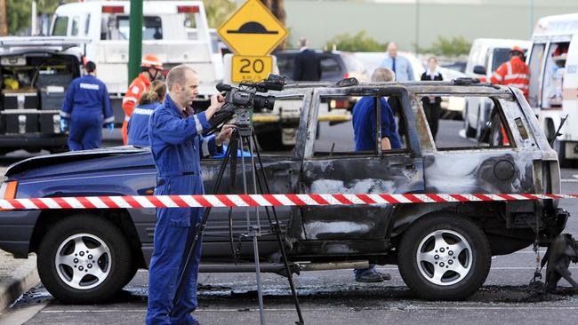 Police examine a burnt out car in East Burwood where James Russouw’s body was found.