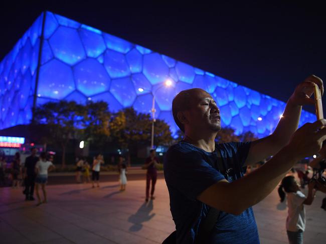 A man takes a photo in front of the Water Cube, which held the 2008 Olympics’ swimming events.