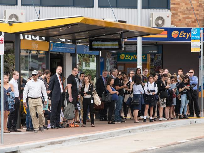 Commuters wait at a B-Line bus stop. Picture: Julian Andrews.