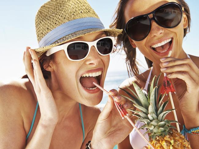 Two friends sipping on a pineapple cocktail while enjoying the summer sun by the pool