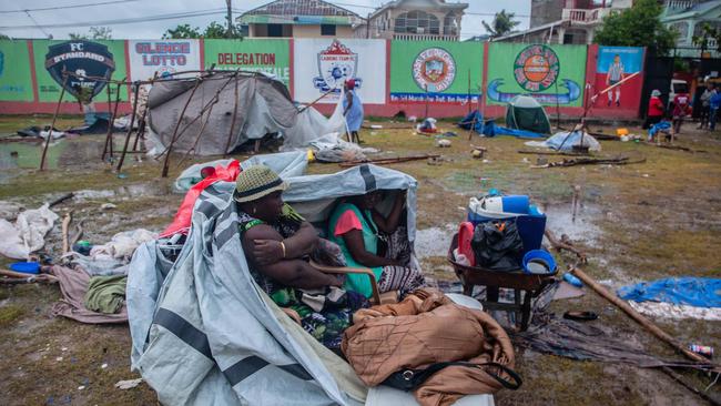 Two women take shelter after being hit by Tropical Storm Grace at an improvised refugee camp at Parc Lande de Gabion stadium in Haiti.