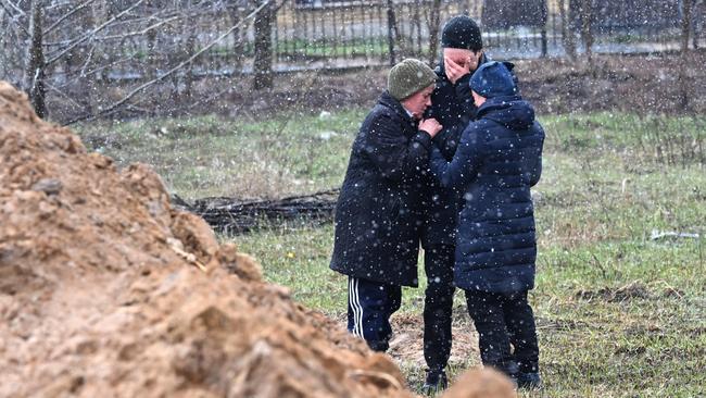 Bucha citizens comfort each other beside a mass grave in the town. Picture: AFP.