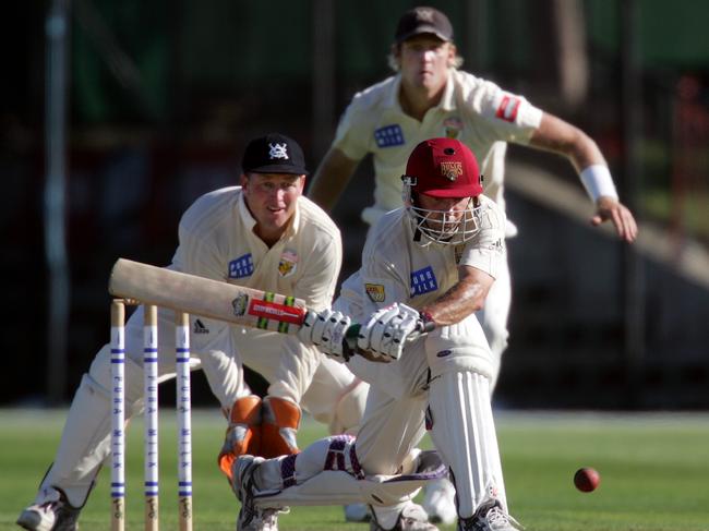 Nathan Pilon watches on as Queensland great Jimmy Maher plays a reverse sweeps in the 2005-06 final.  