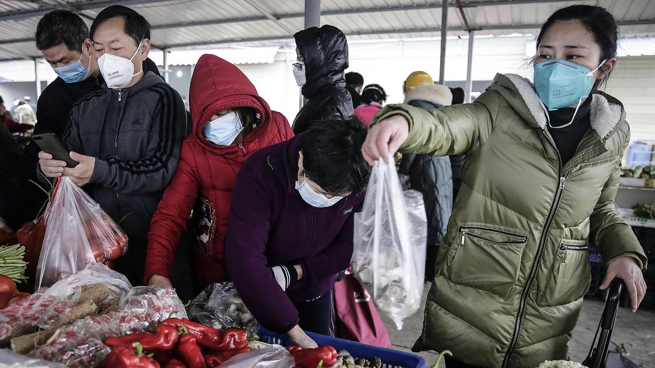 Wuhan residents wear masks to buy vegetables in the market. Picture: Getty Images