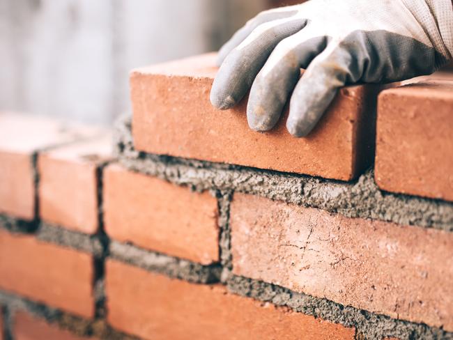 Close up of industrial bricklayer installing bricks on construction site. tradesman generic