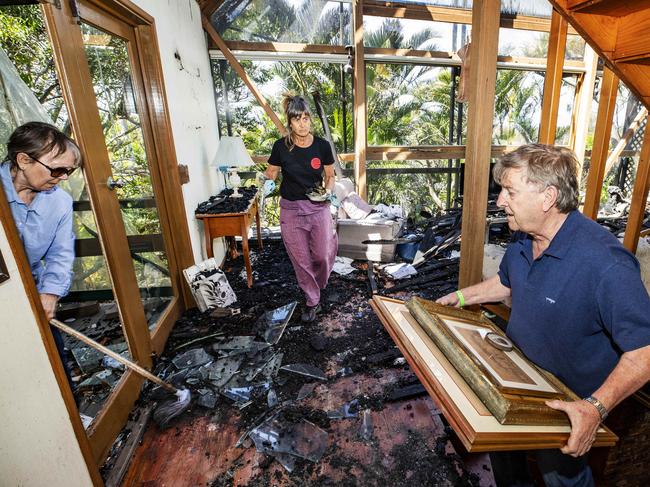 Neighbours Jackie (far left) and Lester Harding help clean up at Pam Murphy's after it was destroyed by bushfire. Picture: Lachie Millard