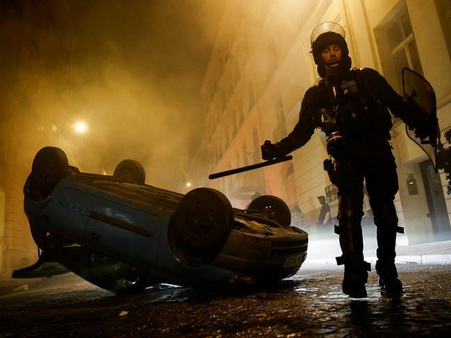 French riot police officers walk next to a vehicle upside down during the fifth day of protests following the death of Nahel, a 17-year-old teenager killed by a French police officer in Nanterre during a traffic stop, in Paris, France, July 2, 2023. REUTERS/Juan Medina