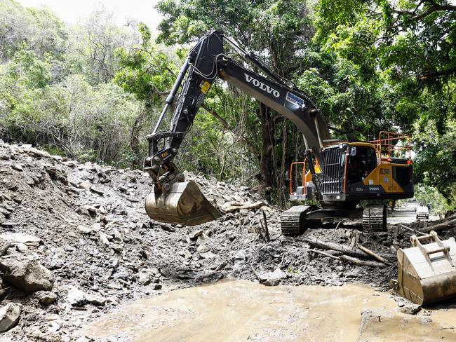 An excavator clears debris from a huge landslide covering the Captain Cook Highway at Ellis Beach. Picture: Brendan Radke