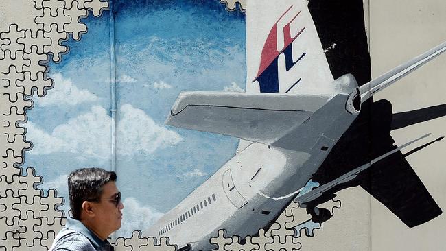 A Malaysian man walks in front of a mural of missing Malaysia Airlines MH370 plane in a back-alley in Shah Alam.