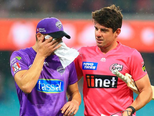 SYDNEY, AUSTRALIA - JANUARY 16: David Miller of the Hurricanes (L) wipes his face as he walks off with Moises Henriques of the Sixers after rain stopped play during the Big Bash League match between the Sydney Sixers and the Hobart Hurricanes at the Sydney Cricket Ground on January 16, 2020 in Sydney, Australia. (Photo by Jenny Evans/Getty Images)