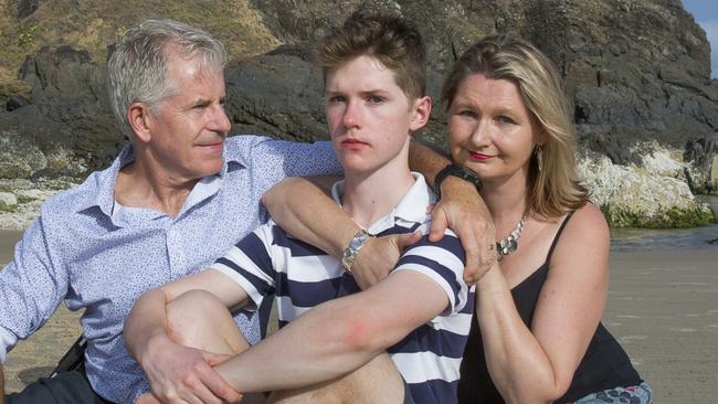 Connor Meldrum (middle) with father David Meldrum and mother Kim Goodrick at Cosy Corner Tallows Beach Byron Bay. Connor fell from the cliff face at Cape Byron in 2019, shattering his skull which left him with severe brain injuries. Since then Connor now 17, has gone through several significant operations, and showing remarkable courage, is now in Year 12 at Trinity College. Photo by Natalie Grono